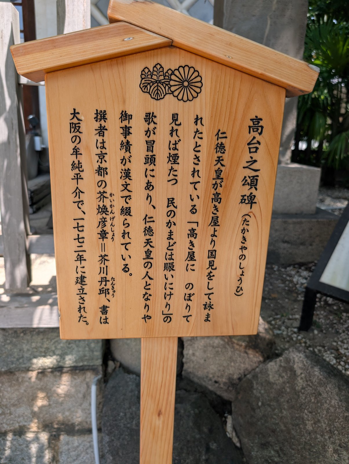 境内の木札「高台之頌碑」。碑の冒頭に「高き屋に」の歌があると書かれている