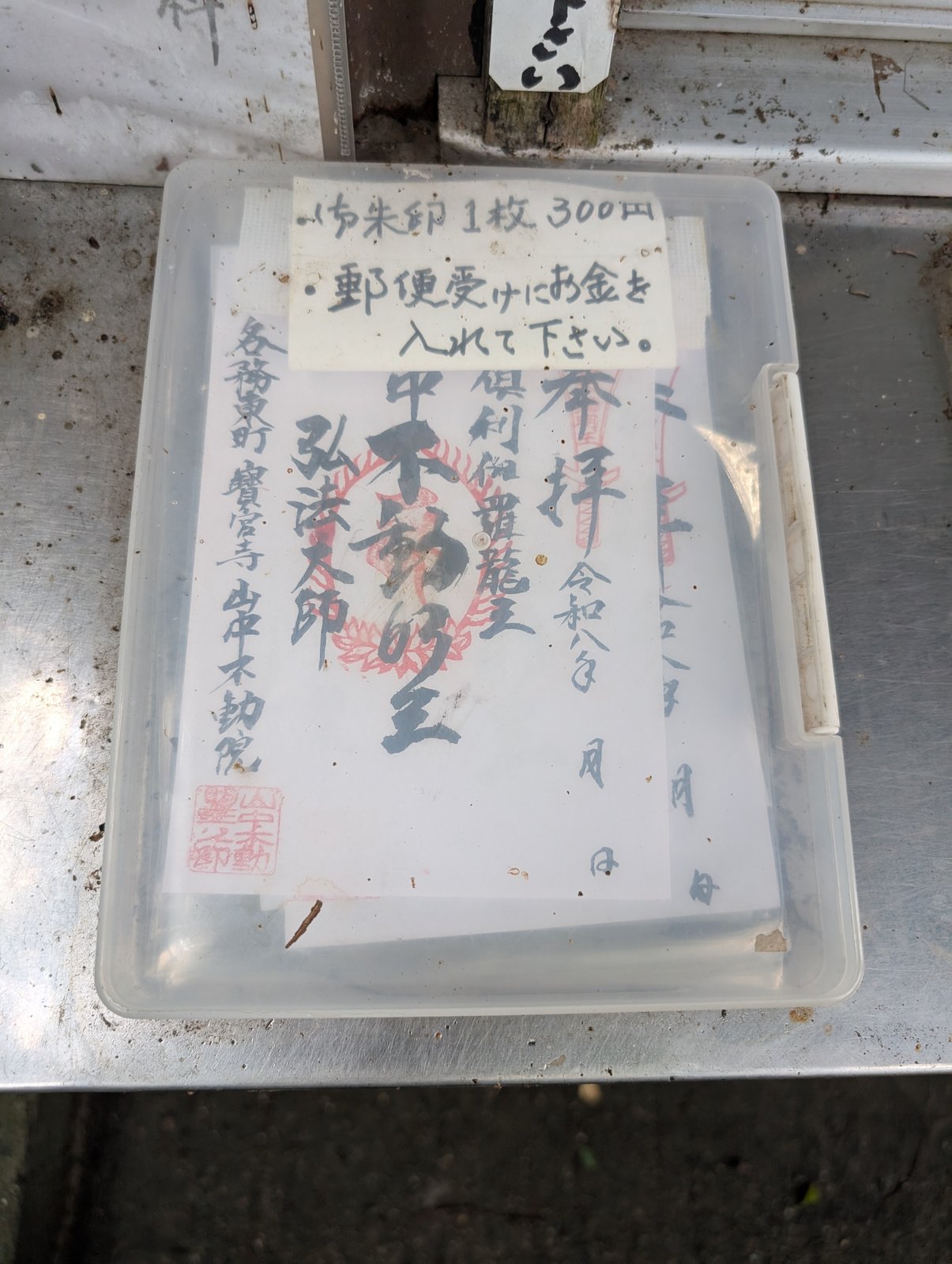 参道脇のケースに入った御朱印と、手書きの貼り紙