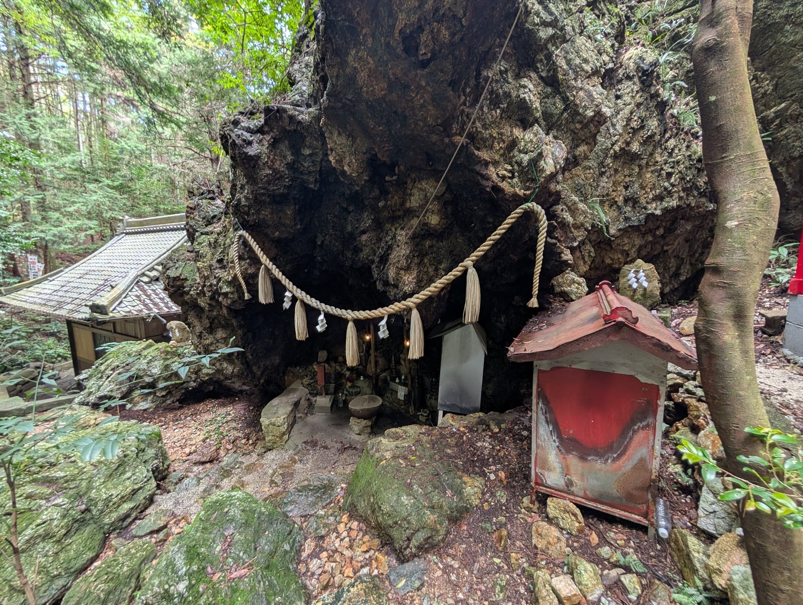大岩のえぐれた洞に注連縄を張り、祠と石仏を祀る岩屋